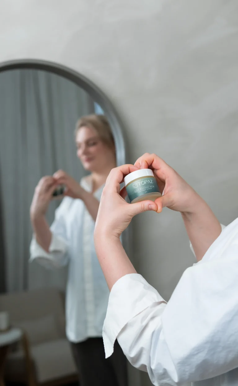 Skincare product held in front of a studio mirror